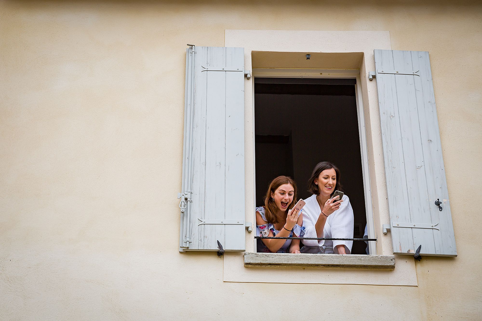 girls lean out of window on the phone