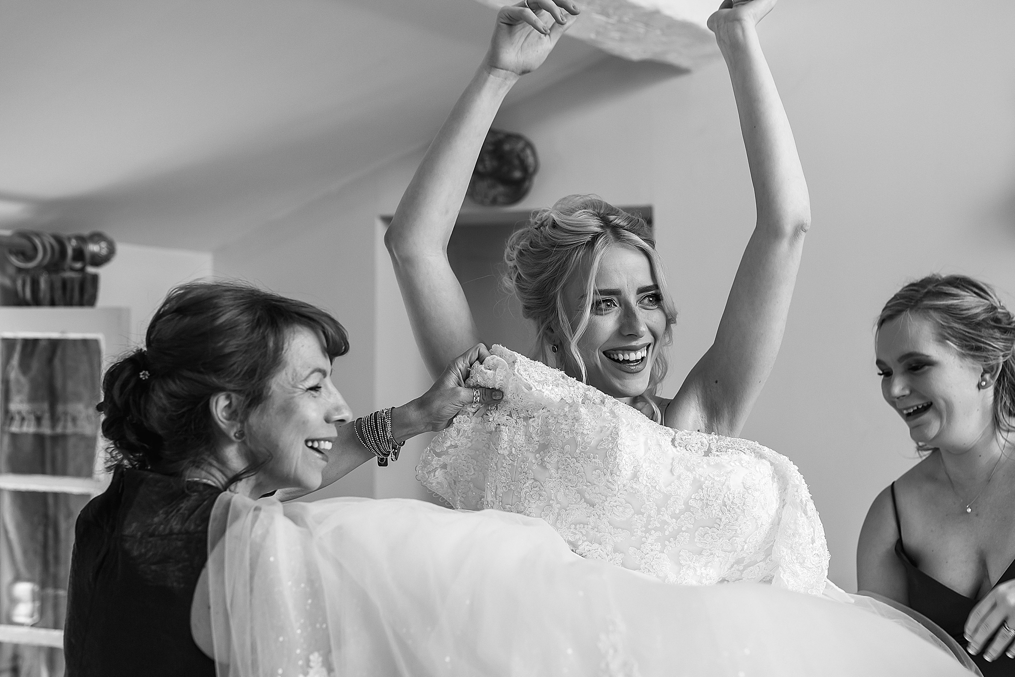 bride smiling and putting on bridal gown